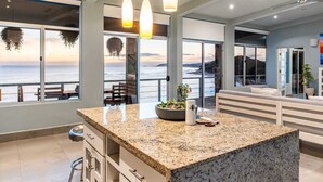 A modern kitchen with a granite countertop, pendant lights, and a view of the ocean. - Penthouse con vista al oceano (Tola)