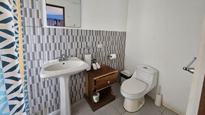 A bathroom with a white sink, wooden vanity, and a toilet. - Chalet con vista al Océano (Tola)