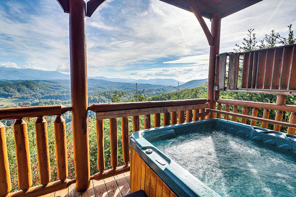 Ein Whirlpool auf einer Holzterrasse mit Blick auf eine gebirgige Landschaft.
