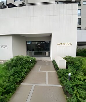 A building entrance with a pathway leading to a glass door, labeled 'AVANZZA' and '25088'.