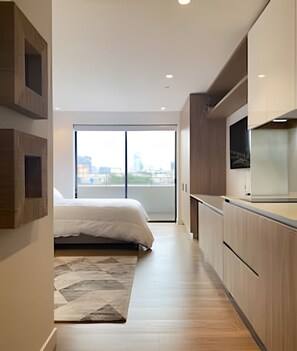 A modern bedroom with a large bed, a view of the city through a large window, and a minimalist design.