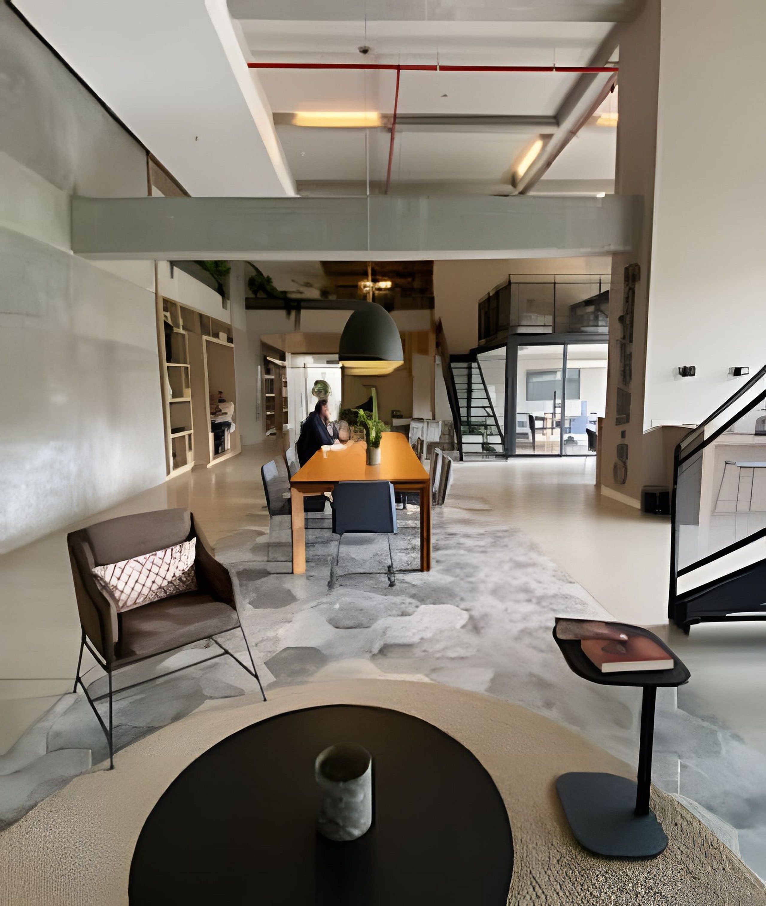 A spacious, modern interior with a central dining table, a comfortable seating area, and a staircase leading to an upper level.