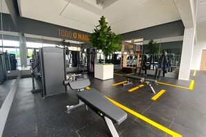 A modern gym with various exercise equipment, including benches and weight machines.