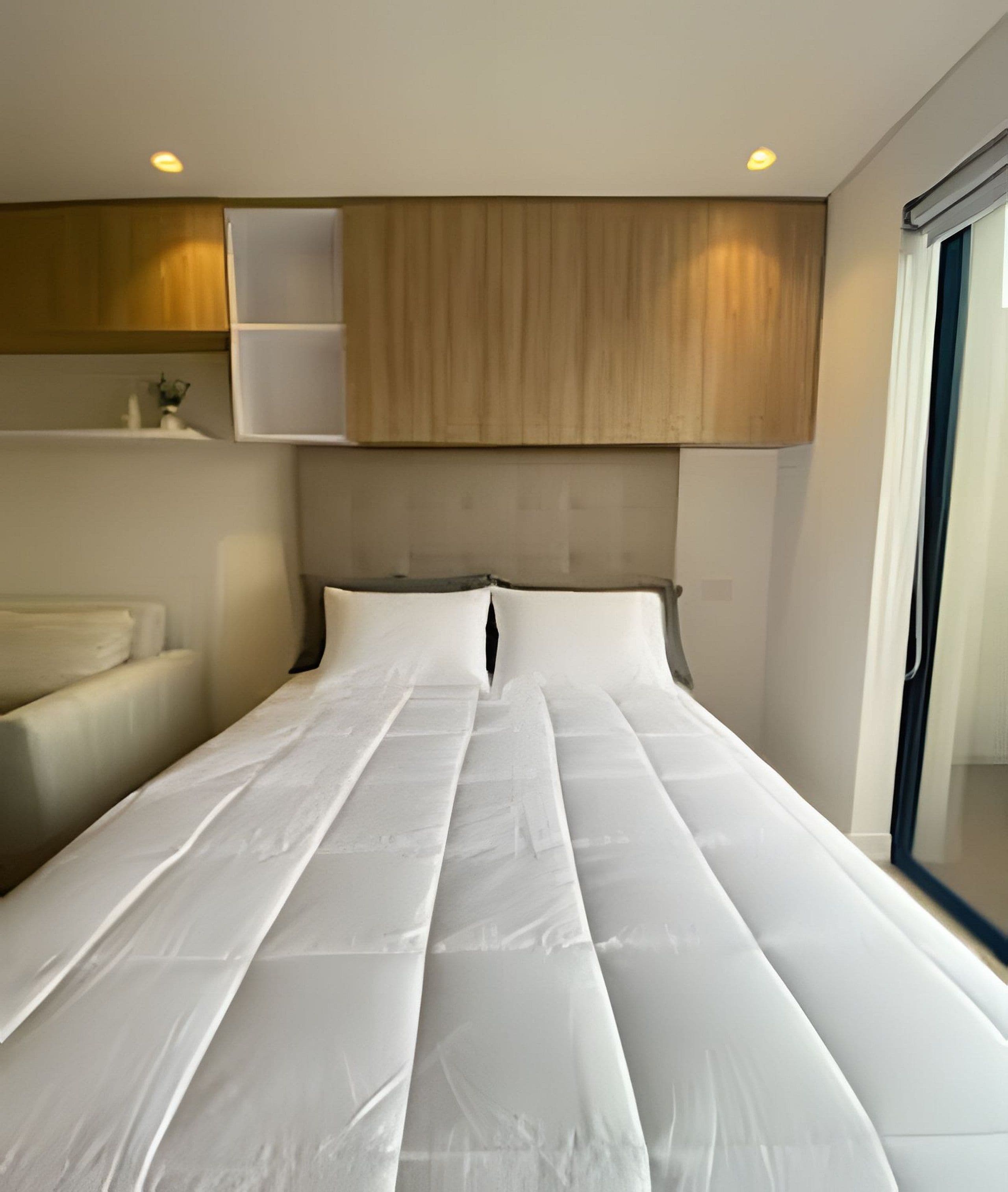 Una habitación de hotel moderna con una cama grande, cabecera de madera y una ventana con vistas.