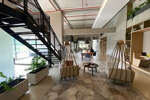 A spacious interior with a central staircase, hexagonal stone flooring, and modern furniture.
