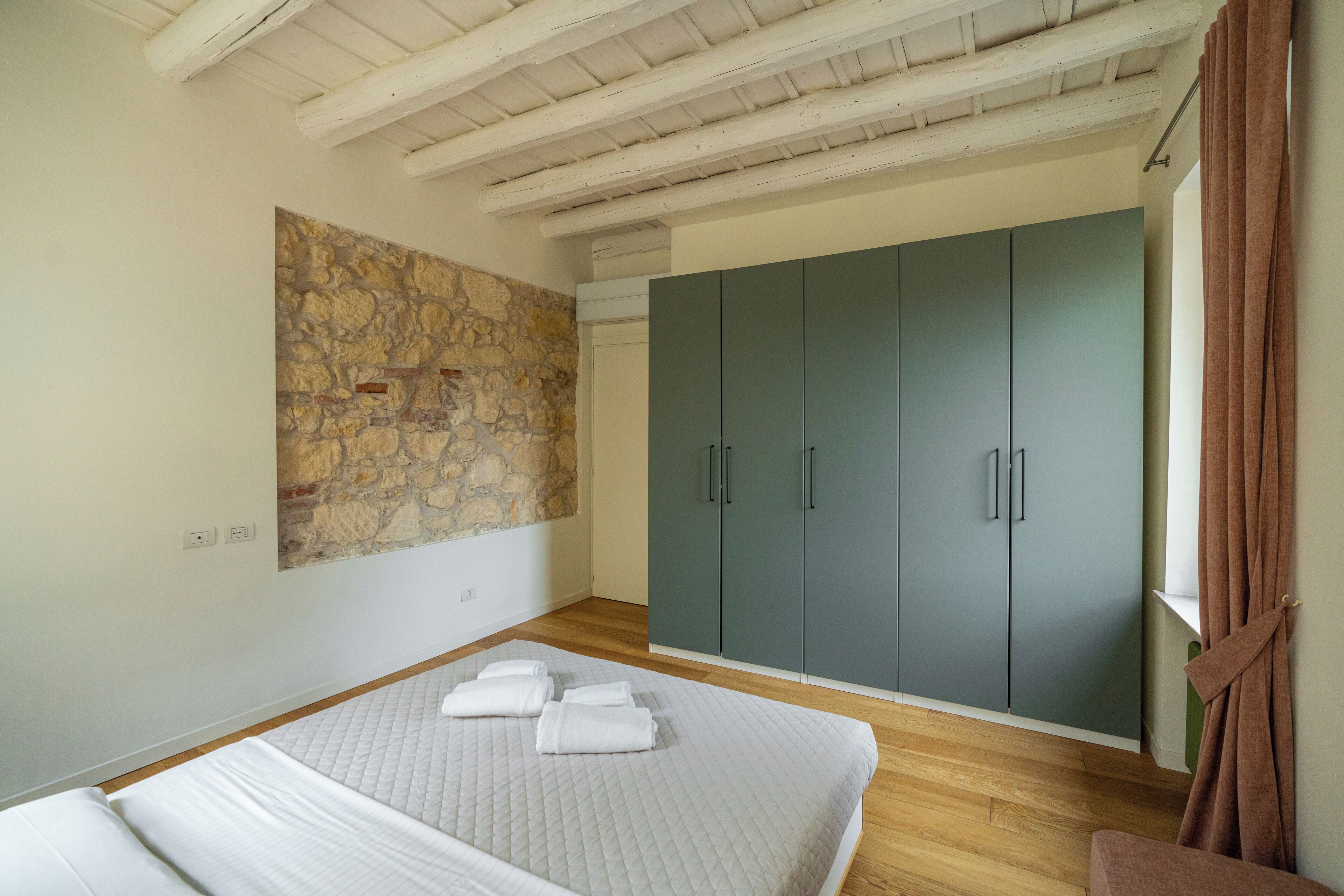 Un dormitorio con cama, pared de piedra y armario.