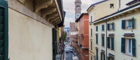 Una calle estrecha flanqueada por edificios, una torre del reloj a lo lejos, y algunos coches estacionados.