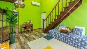 A room with a green wall, a wooden staircase, a dining area with a table and chairs, and a large potted plant. - Beijing Shixi Inn near Forbidding City (Beijing)