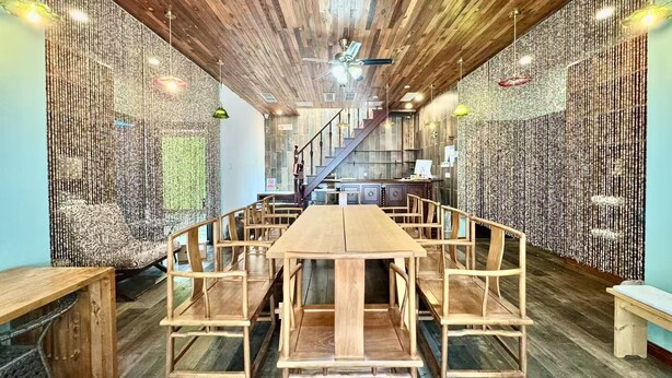 A wooden dining area with a high ceiling and a staircase in the background. - Beijing Shixi Inn near Forbidding City (Beijing)