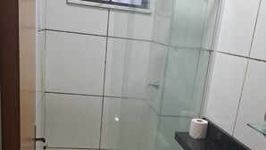 Un bagno piccolo e compatto con il water, una cabina doccia in vetro, un lavandino e un portasciugamani.