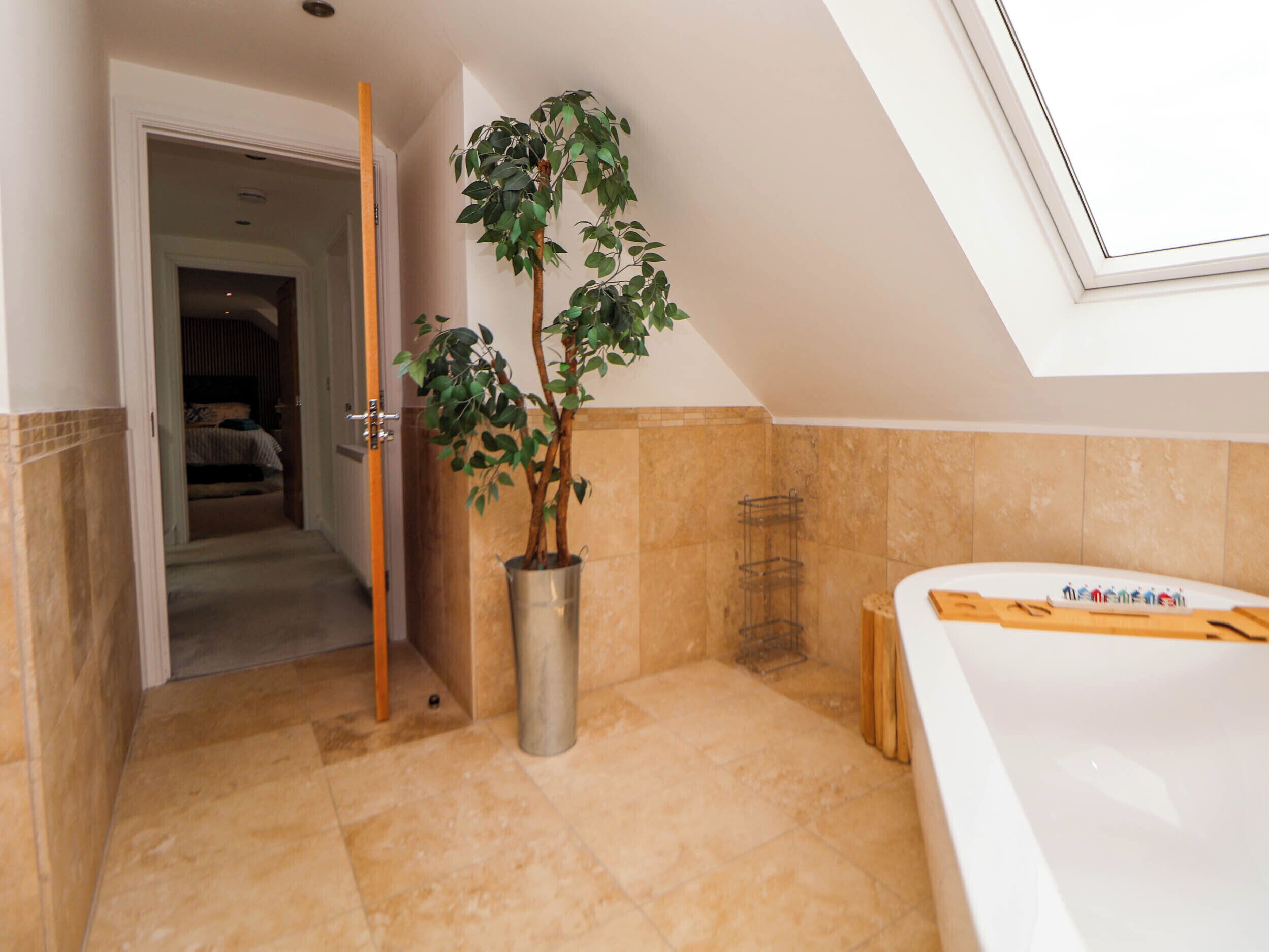 A bathroom with a bathtub, a potted plant, and a shower area.