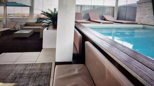A modern indoor pool area with lounge chairs and a view of the city. - Water lily 5 star wellness (Caorle)