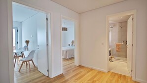 Een modern interieur met een houten vloer, een zithoek met stoelen, een bed en een douchehoek.