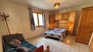Une chambre à coucher avec un lit, un canapé, des meubles en bois et un luminaire suspendu.