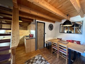 Un interno rustico in legno con zona pranzo, cucina e scala.