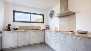A modern kitchen with a window, a clock, and a coffee maker.