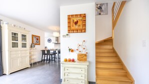 A modern kitchen with a white cabinet, a wooden staircase, and a dining area with a table and chairs.