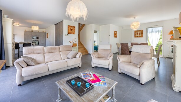 A spacious living room with a sofa, chairs, a coffee table, and a staircase leading to another level.