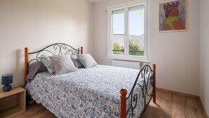 Une chambre à coucher avec un lit, une table de chevet, une fenêtre et un tableau accroché au mur.