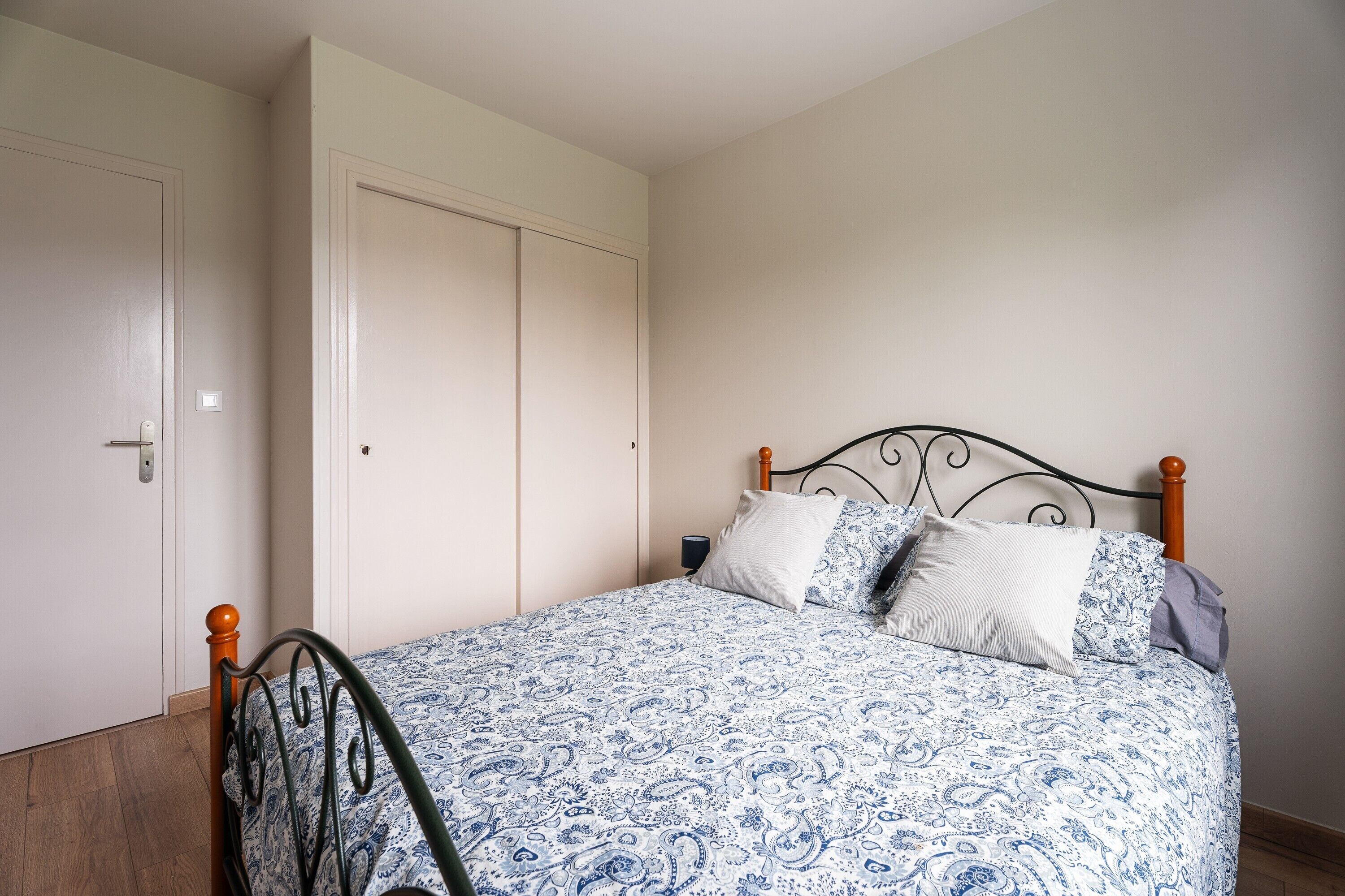 Een slaapkamer met een bed, een kledingkast en een nachtkastje.