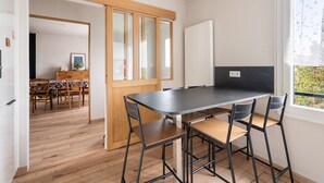 Une cuisine moderne dotée d’un grand îlot central, d’un plancher en bois et offrant une vue sur un jardin grâce à une fenêtre.