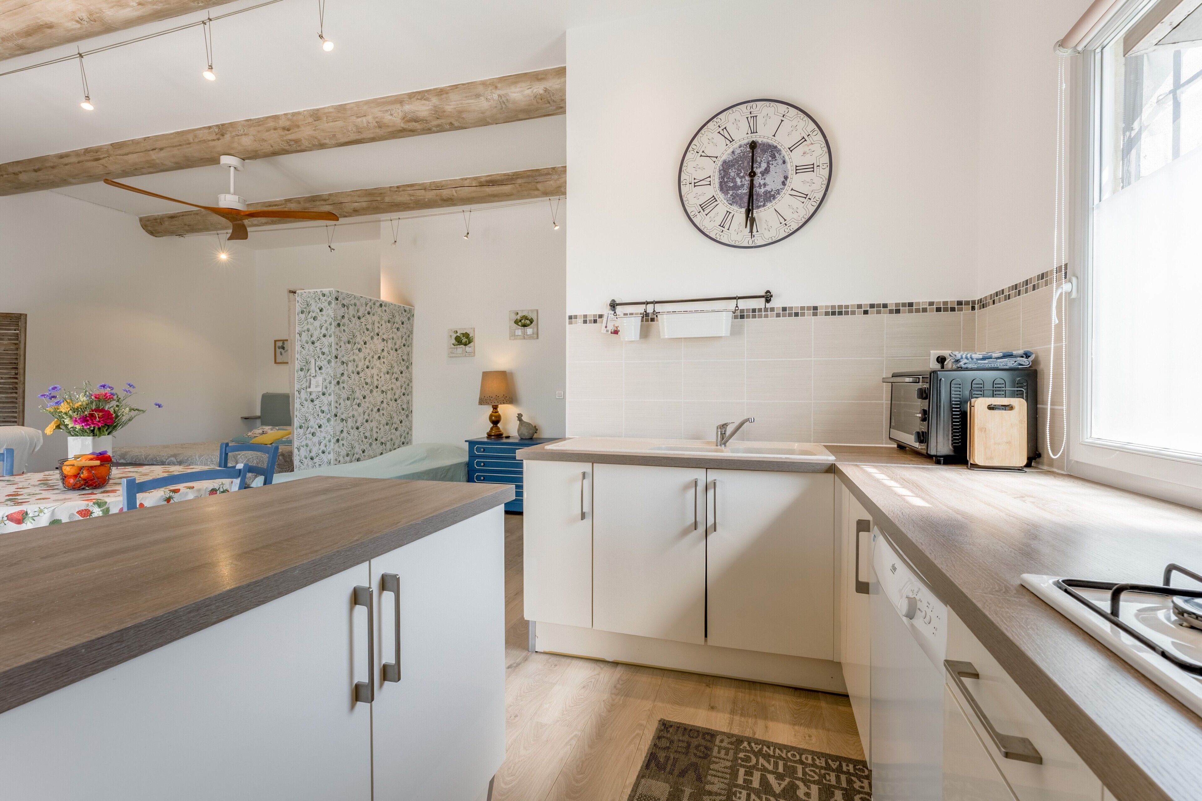 Une cuisine moderne avec un plafond en bois, une horloge murale et une fenêtre.