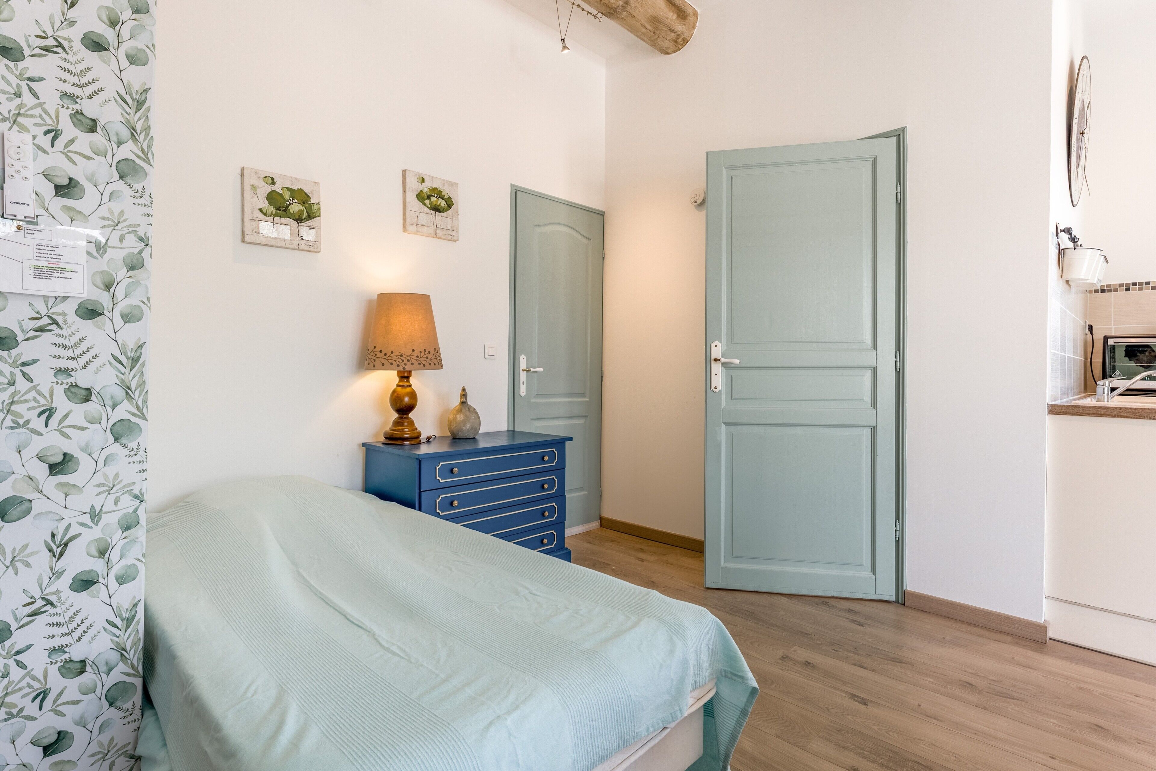 A bedroom with a bed, a dresser, a lamp, and two doors.