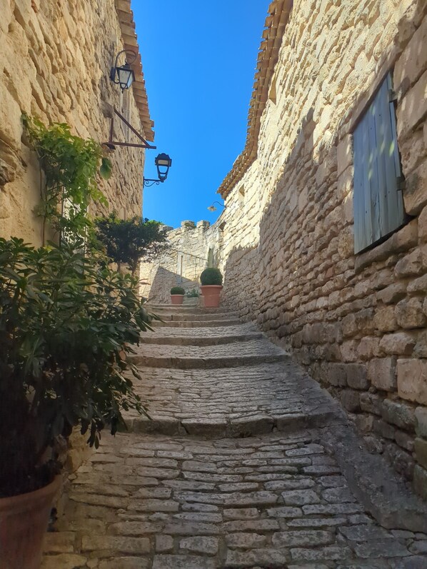 Una estrecha escalera de piedra que sube a un edificio con puerta de madera y una ventana pequeña.