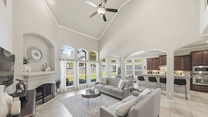 A spacious living room with a fireplace, a sofa, a coffee table, and a dining area with bar stools. - Cozy, Quiet 4-bedroom, 3.5 bathroom Home in The Woodlands (Magnolia)