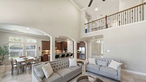 A spacious living area with a high ceiling, a dining area, and a kitchen. - Cozy, Quiet 4-bedroom, 3.5 bathroom Home in The Woodlands (Magnolia)