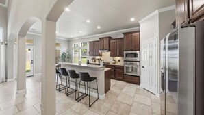 A spacious kitchen with a central island, bar stools, stainless steel appliances, and a view to the outside. - Cozy, Quiet 4-bedroom, 3.5 bathroom Home in The Woodlands (Magnolia)