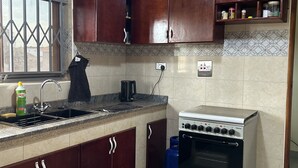Cuina amb armaris de fusta fosca, fogó de gas, rentapelats i finestra amb reixatge metàl·lic.