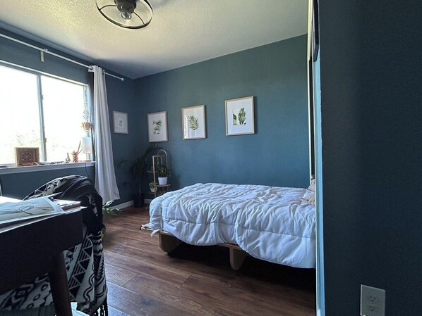 A bedroom with a bed, a window with curtains, and framed pictures on the wall. - Adults only Sanctuary & Writer's Retreat (Manchaca)