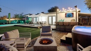 Une terrasse extérieure dotée d’un foyer, de sièges, d’un jacuzzi et d’un espace bar.