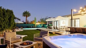 Un espace extérieur bien aménagé, comprenant un patio, un jacuzzi, des chaises longues et une piscine.