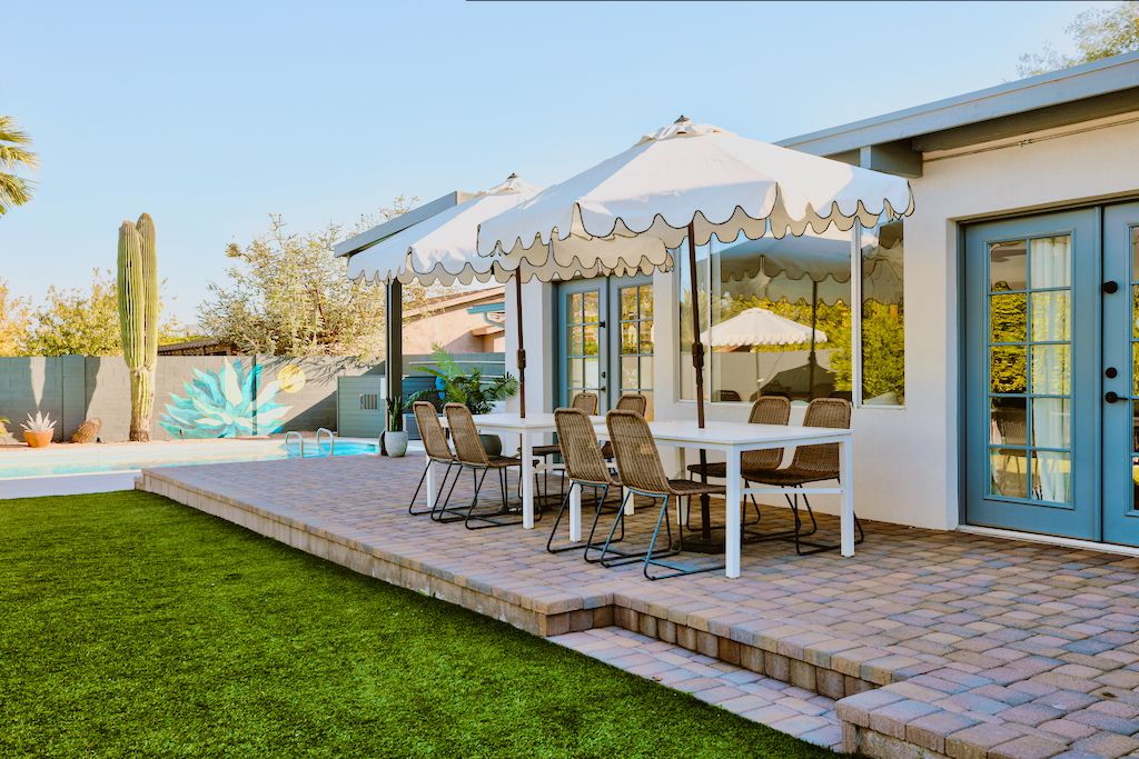 A patio with a table and chairs, a pool, and a cactus.