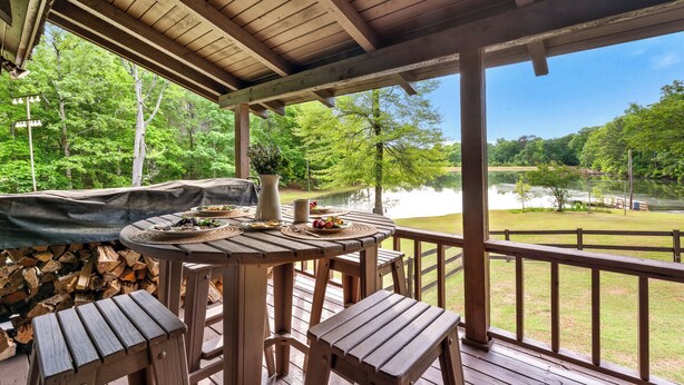 Une terrasse en bois avec une table et des bancs, offrant une vue sur un lac et une forêt.