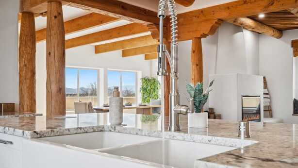 Una cucina con piani in marmo, un lavello e travi in legno.