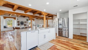 Una cucina moderna con travi in legno, mobili bianchi e un frigorifero in acciaio inossidabile.