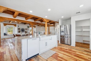 Una cocina moderna con vigas de madera, armarios blancos y un refrigerador de acero inoxidable.