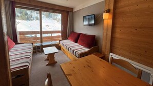 Ein gemütliches Blockhausszimmer mit einem Bett, einer Couch, einem Tisch und einem Fernseher.
