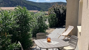 An outdoor patio with a table and chairs, a candle, and a view of a mountain. - Maison Avalone in the heart of the Ardèche Gorges! (Vallon-Pont-d'Arc)