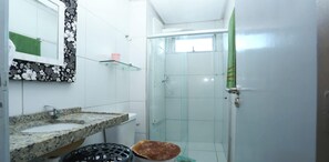 A bathroom with two sinks, a mirror, a shower, and a toilet.