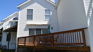 A two-story house with a wooden deck and a green umbrella. - Tori's Landing- Limited Water View Shared Pier Access (Chincoteague)