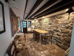 A stone wall, a wooden dining table with chairs, and a patterned rug.