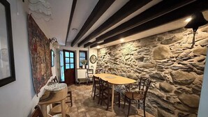 A dining area with a stone wall, wooden table, and chairs.
