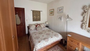 A bedroom with a bed, a dresser, a lamp, and a door.
