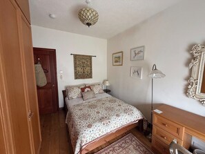A bedroom with a bed, a dresser, a lamp, and a door.