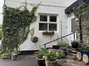 A white building with a window, a staircase, and various potted plants. - Elegant 4-Bed Pet-Friendly Retreat in Snowdonia (Conwy Principal Area)