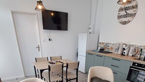 A modern living room with a sofa, two armchairs, a coffee table, and a dining area with a table and chairs.